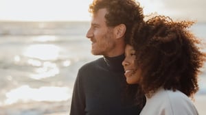 Couple on the beach with the sea in the back looking into the distance