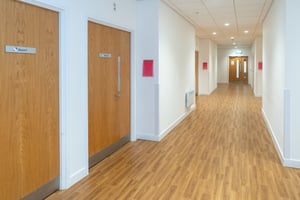 Corridor inside Care Fertility Cheshire in Warrington with consultation room doors and bright, modern interior.