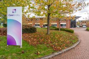 Exterior view of Care Fertility Cheshire clinic at Daresbury Park, Warrington, showing the Care Fertility sign and building entrance surrounded by trees and autumn leaves.