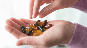 A hand holding a range of vitamins and supplement capsules