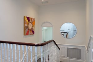 Upstairs landing at Care Fertility Tunbridge Wells with colourful artwork and a round mirror