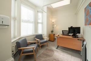 Consultation room at Care Fertility Tunbridge Wells with two armchairs and a desk by the window