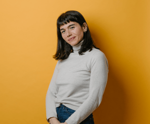 Woman smiling confidently against a yellow background, reflecting optimism and strength during fertility treatment.
