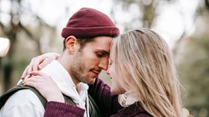 A young heterosexual couple lovingly embracing and looing at one another