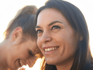 Same-sex female couple laughing with each other.
